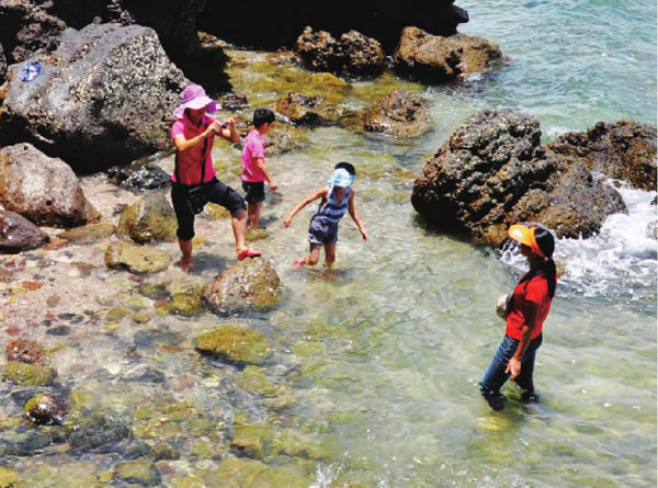 一家人在海边戏水嬉戏，清凉的海水冲走了躁动的暑意。
